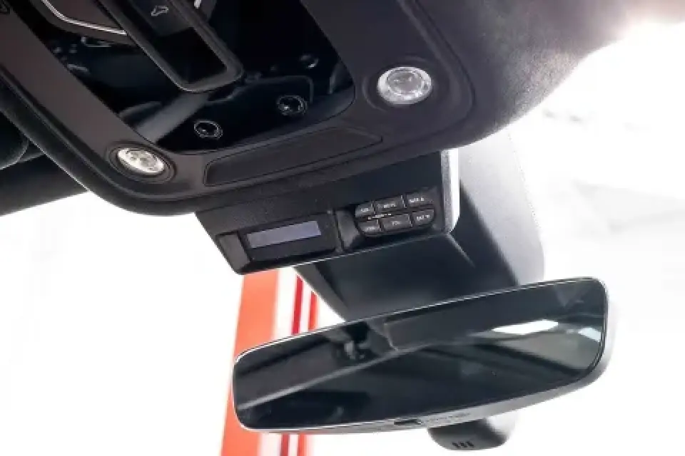 Close-up of a cars rearview mirror and overhead console with control buttons and lights.