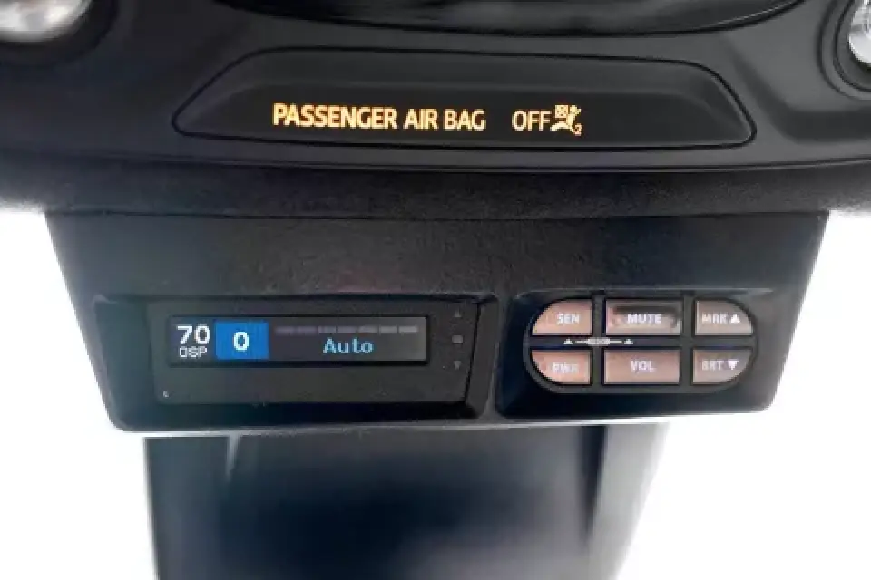 Car dashboard showing PASSENGER AIR BAG OFF and a digital display with control buttons below.