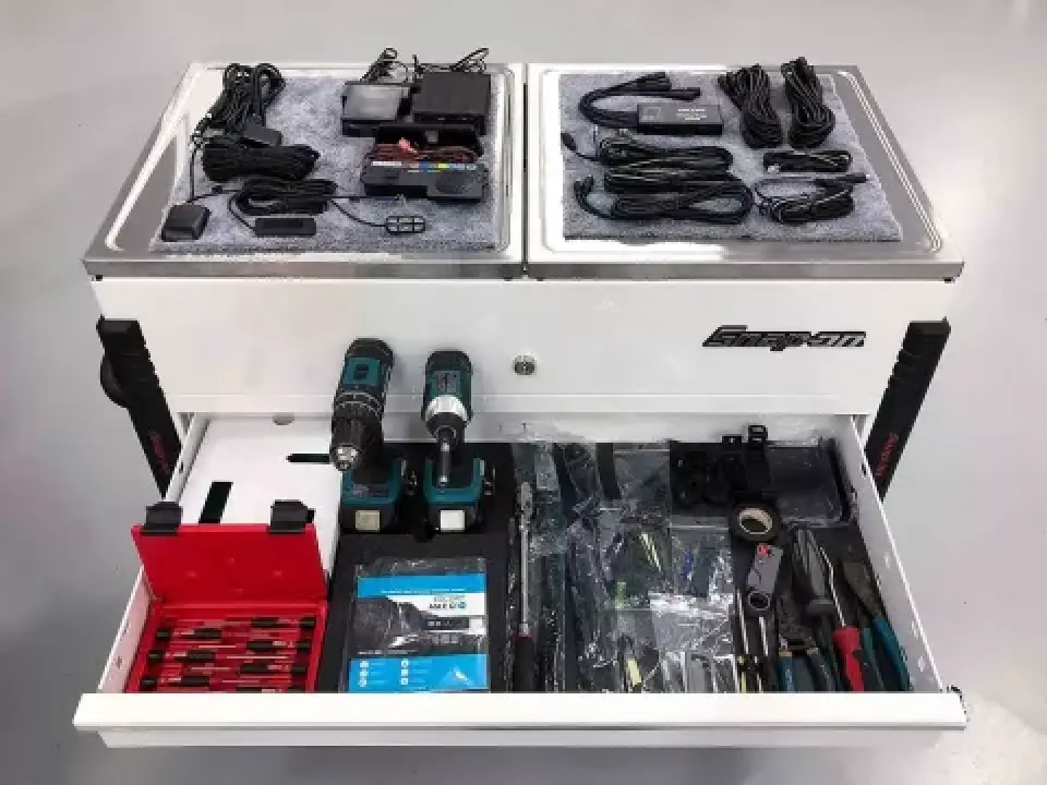 A toolbox with drills, screwdrivers, pliers, chargers, cables, and assorted tools neatly organized.