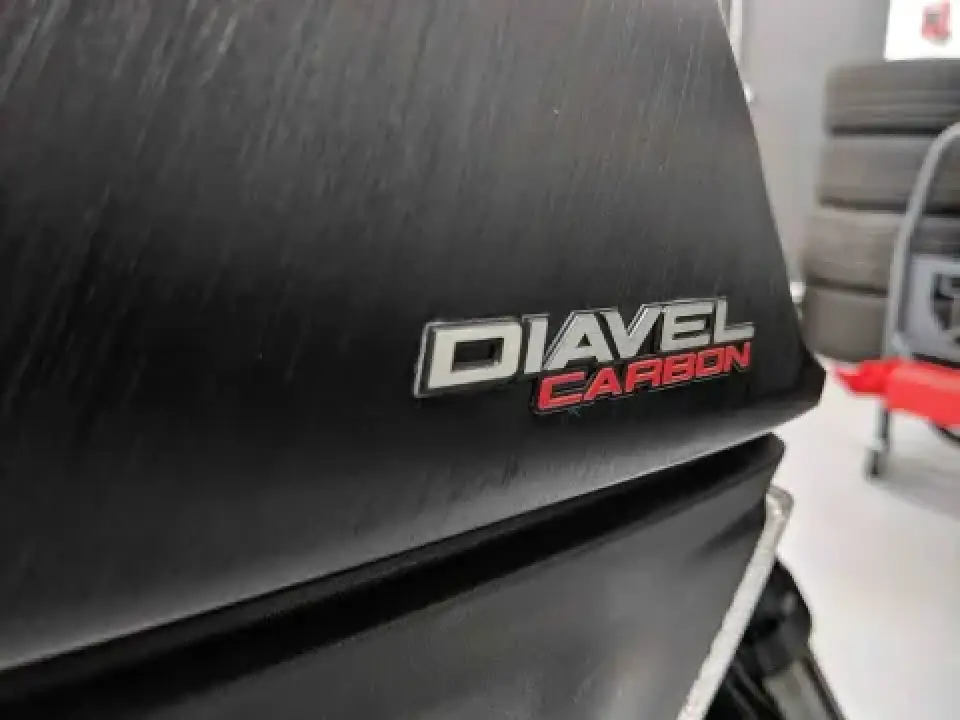 Close-up of a Diavel Carbon emblem on a dark, textured motorcycle body panel.