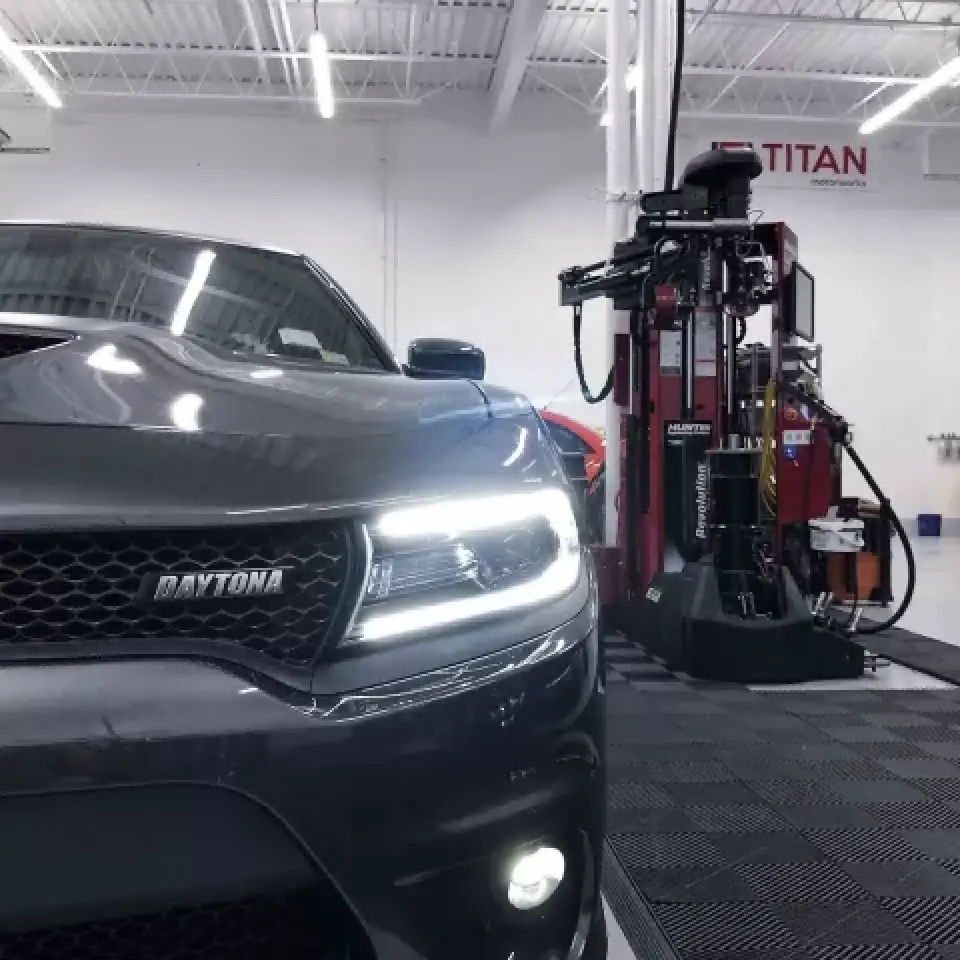 Close-up of a Dodge Daytona car in an automotive workshop with equipment in the background.