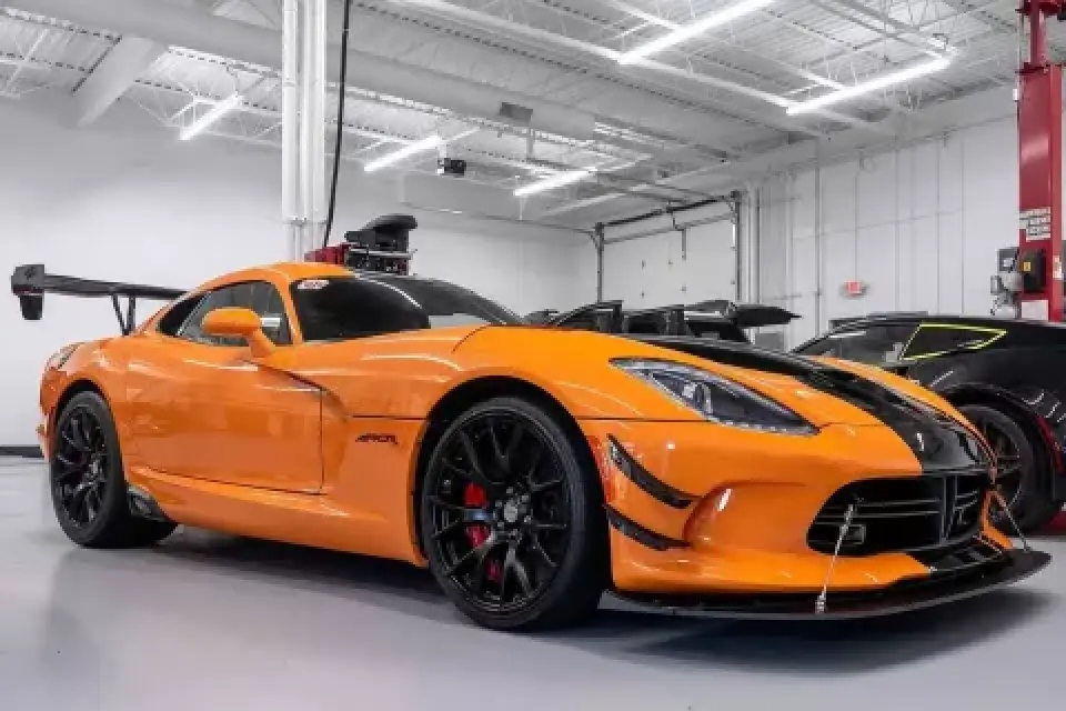 An orange sports car with black accents parked in a well-lit garage.