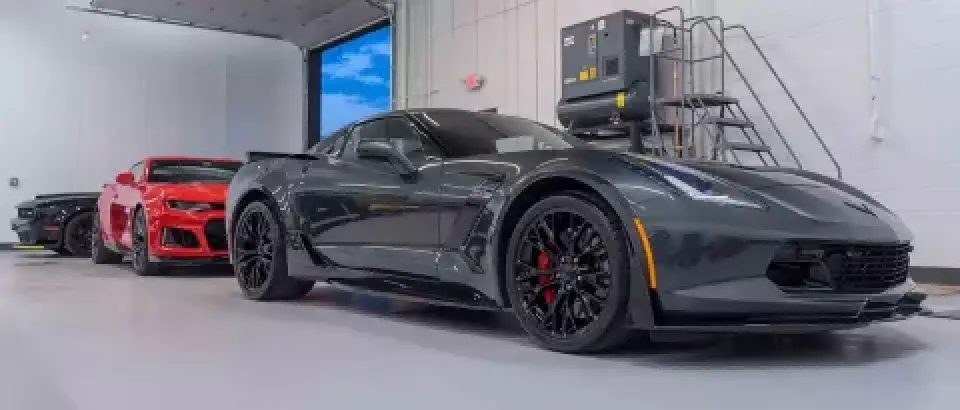 Three sports cars, including a black Corvette, parked inside a clean, modern garage.