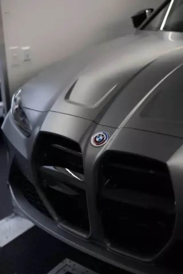 Close-up of the front of a gray BMW car in a garage, showing the grille and logo.