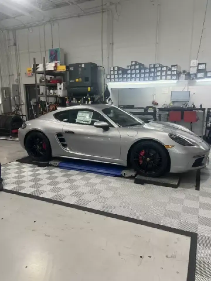 A silver sports car is parked inside a clean, organized automotive workshop.