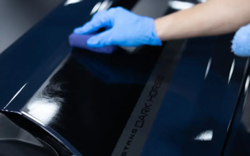 hand with glove detailing car exterior