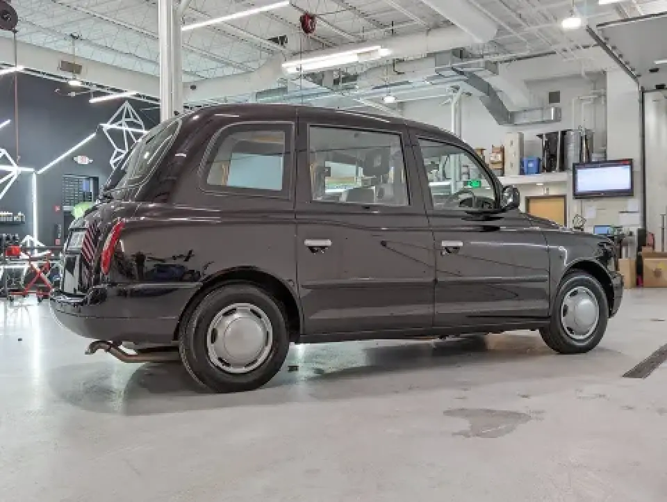 black London taxi parked inside modern garage workshop