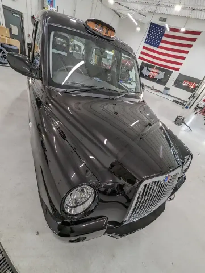 London style taxi parked indoors with American flag background
