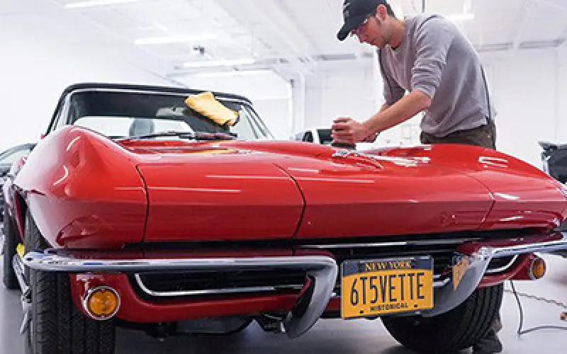 titan motorworks employee waxing a red car