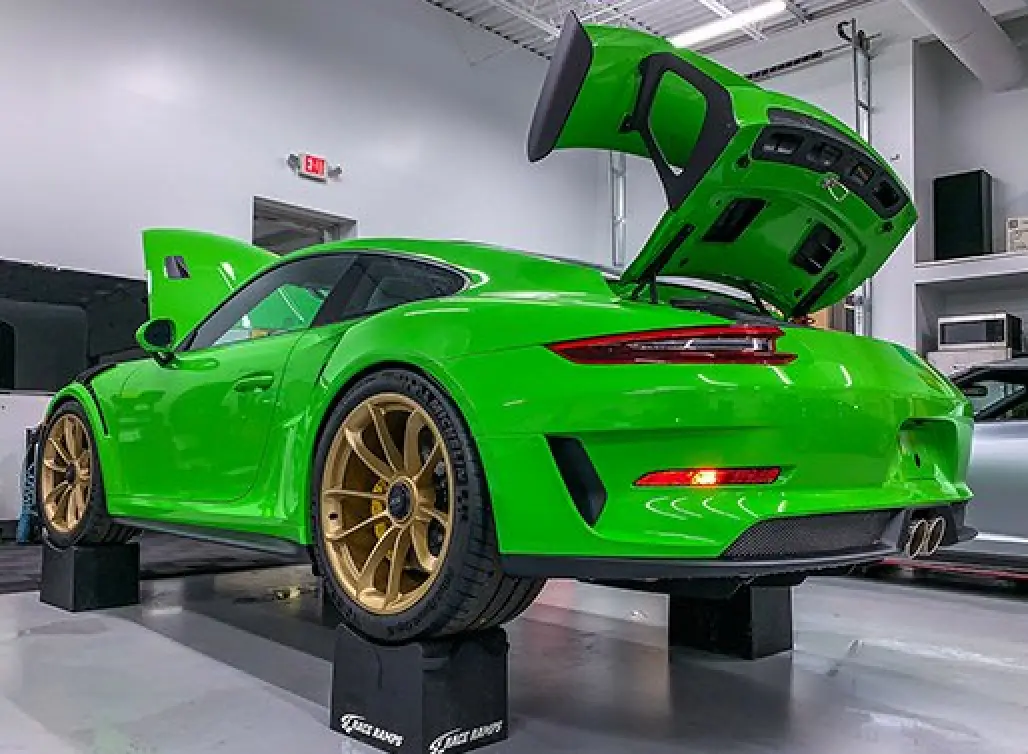 green car lifted with the trunk and hood open
