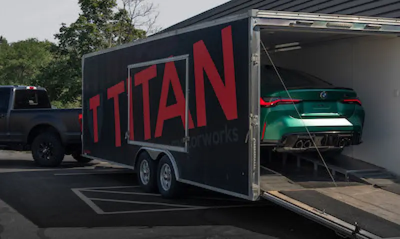 car being transported in a trailer attached to a pickup truck