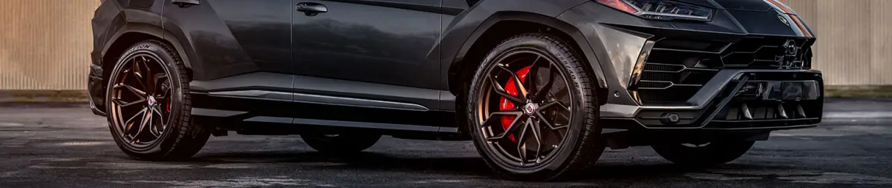 Close-up side view of a black luxury SUV with black wheels and red brake calipers.