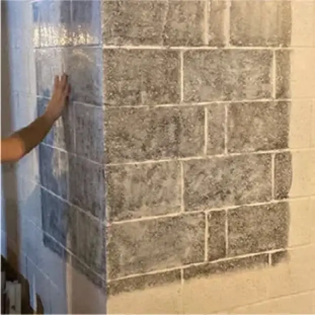A hand touches a corner wall painted to appear like a three-dimensional shaded cube.