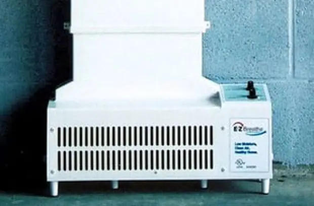 White ventilation unit with air vents, control knob, and label reading EZ Breathe against a wall.