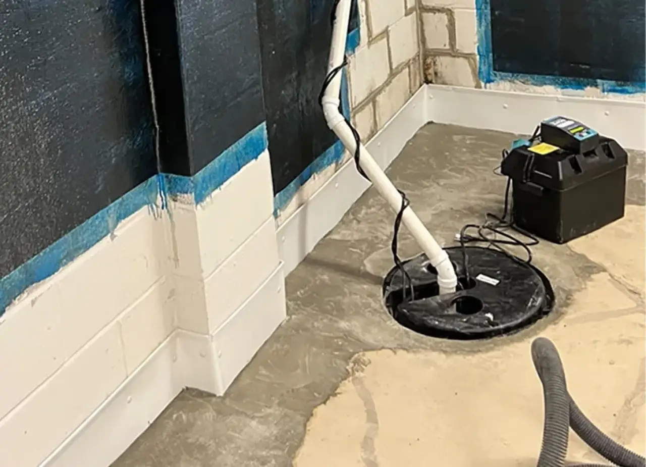 Sump pump system with PVC pipes installed in a basement with painted block walls.