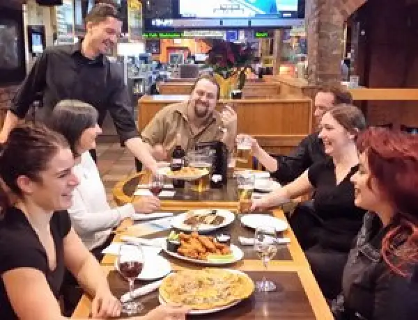 Group laughing around a restaurant table with food and drinks.