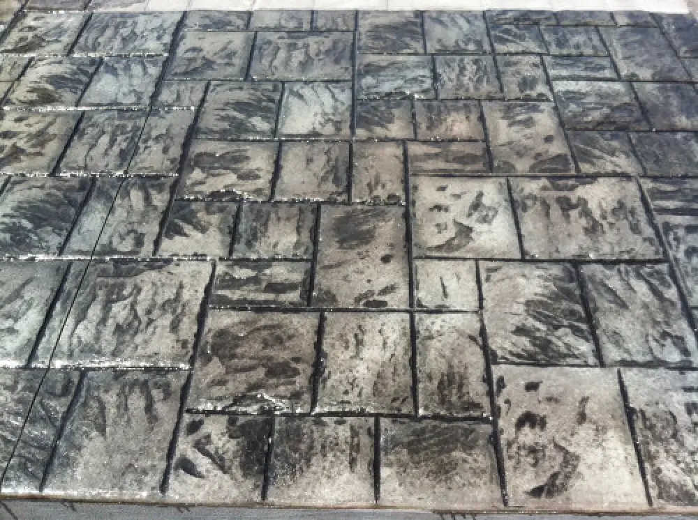 A close-up of a patterned, weathered stone pavement with rectangular and square tiles.