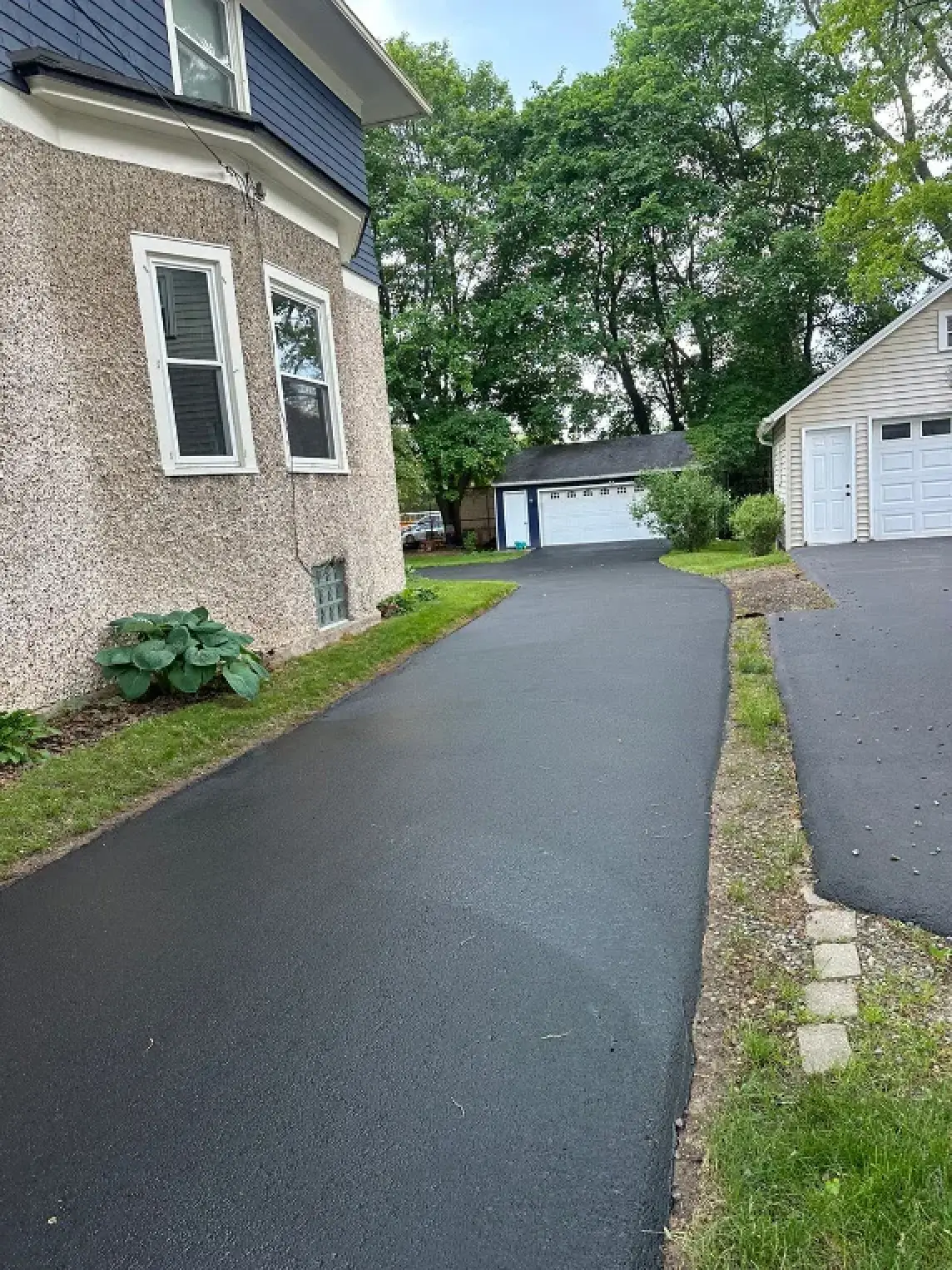 A freshly paved driveway next to a residential home.