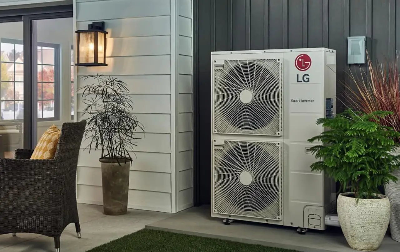Outdoor LG air conditioning unit beside plants and patio furniture near a house entrance.