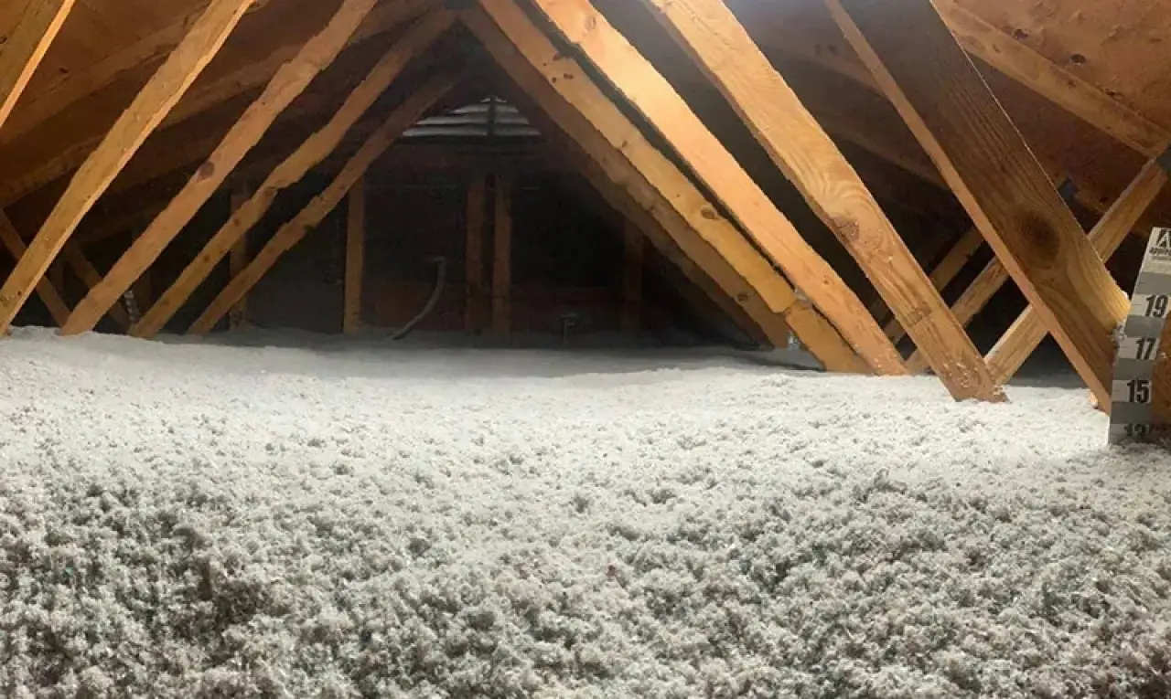 Attic with wooden beams and floor covered in thick white insulation material.