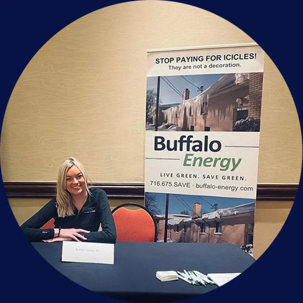 A woman sits at a table with a Buffalo Energy banner displayed behind her.