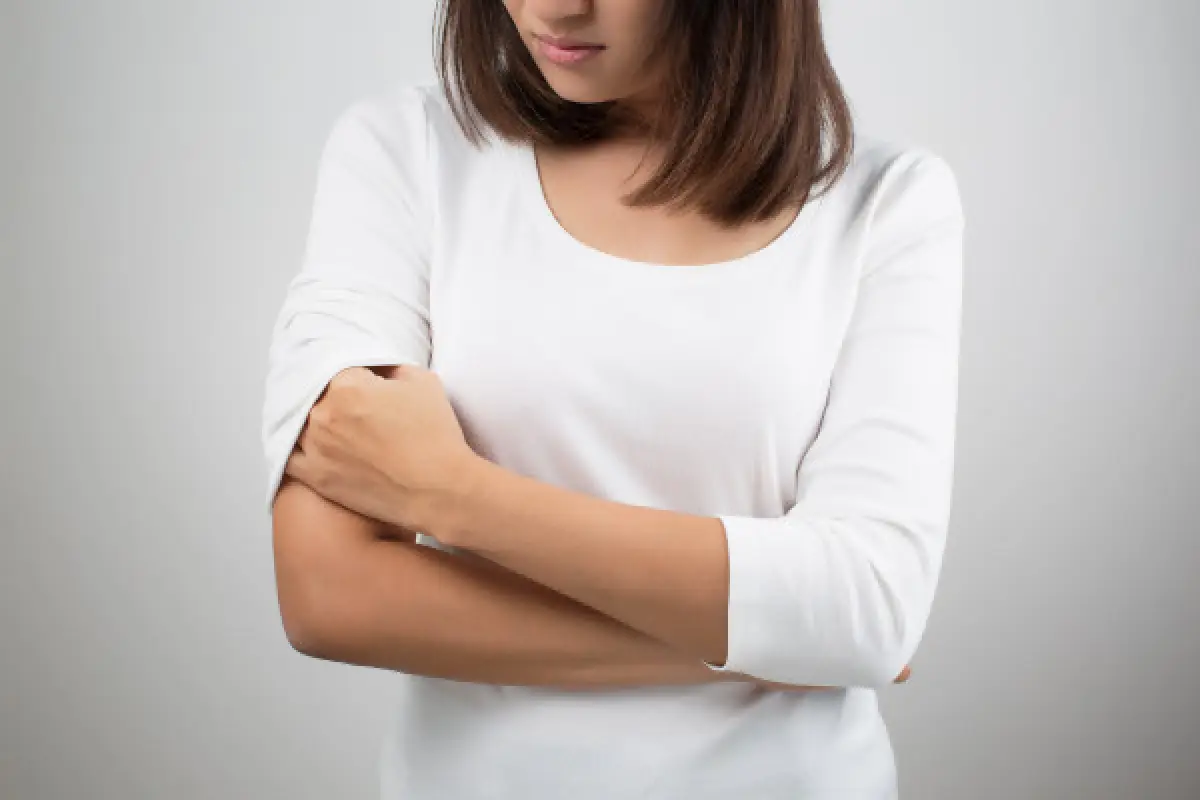 Woman scratching her arm, suggesting itchy eczema symptoms.