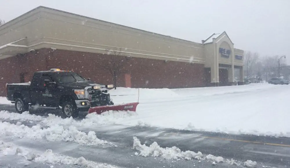black truck snow plowing a commercial parking lot