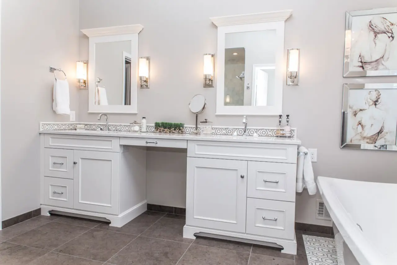 White double vanity with mirrors, sconces, and mosaic tile backsplash.