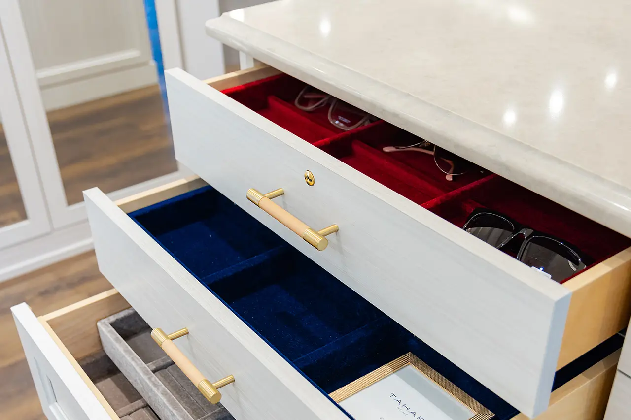 Open closet drawers with velvet-lined compartments for sunglasses and accessories.