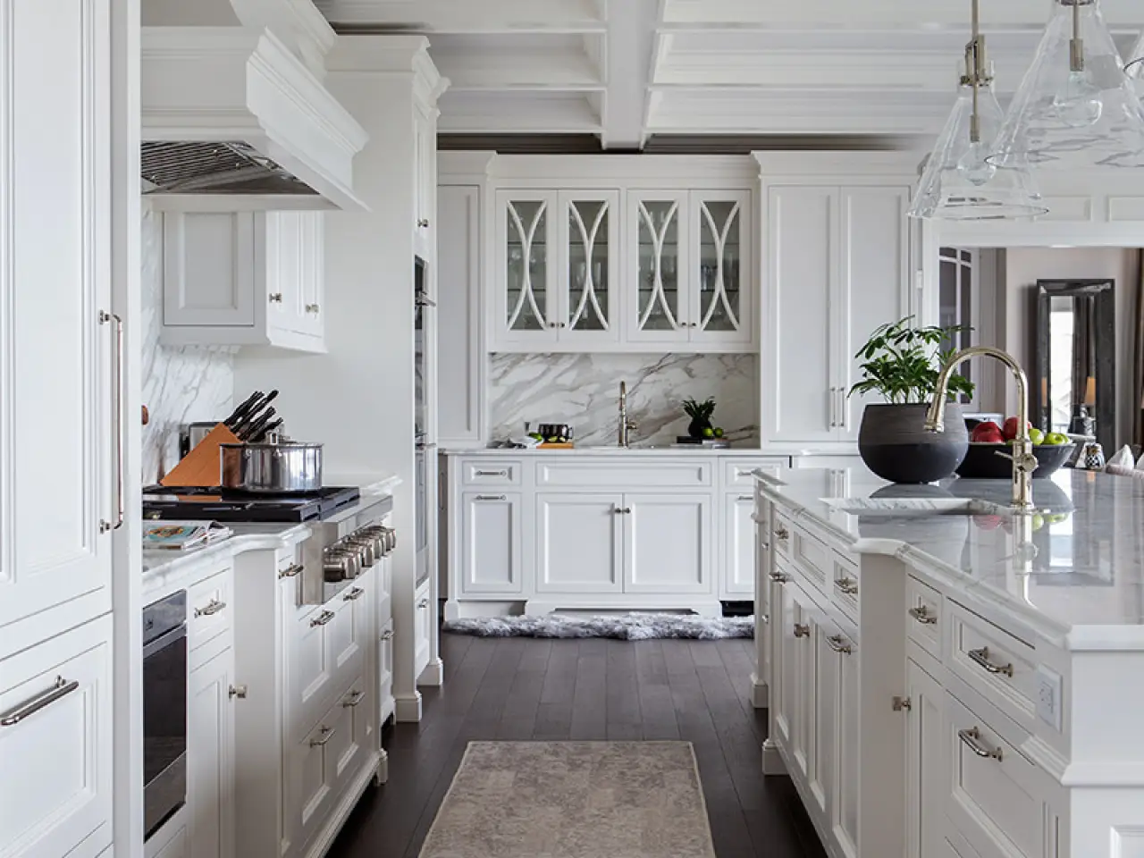 Bright, modern kitchen with white custom cabinets, marble countertops, an island, and stainless steel appliances.