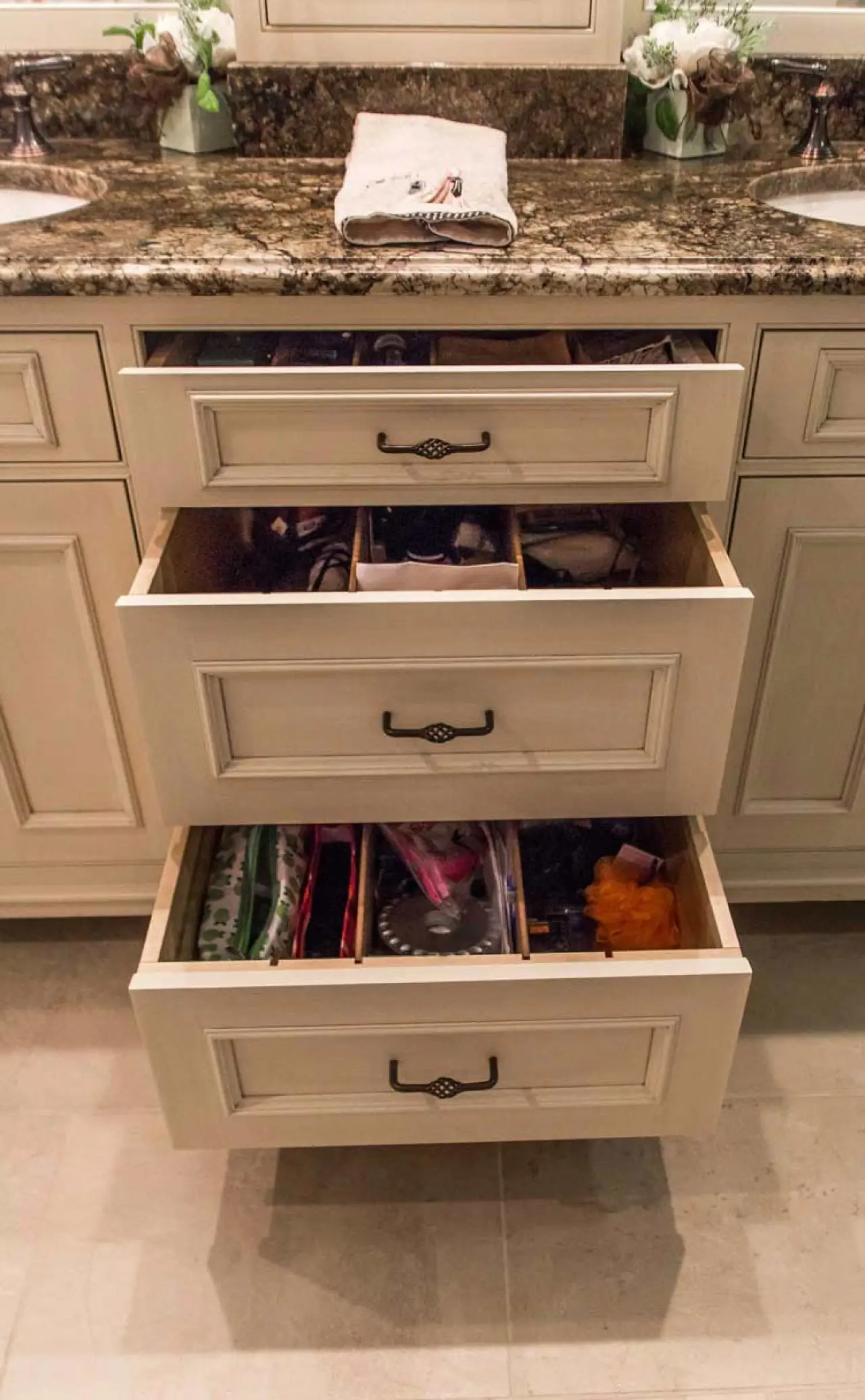 Open vanity drawers beneath an earth-tone granite bathroom countertop.