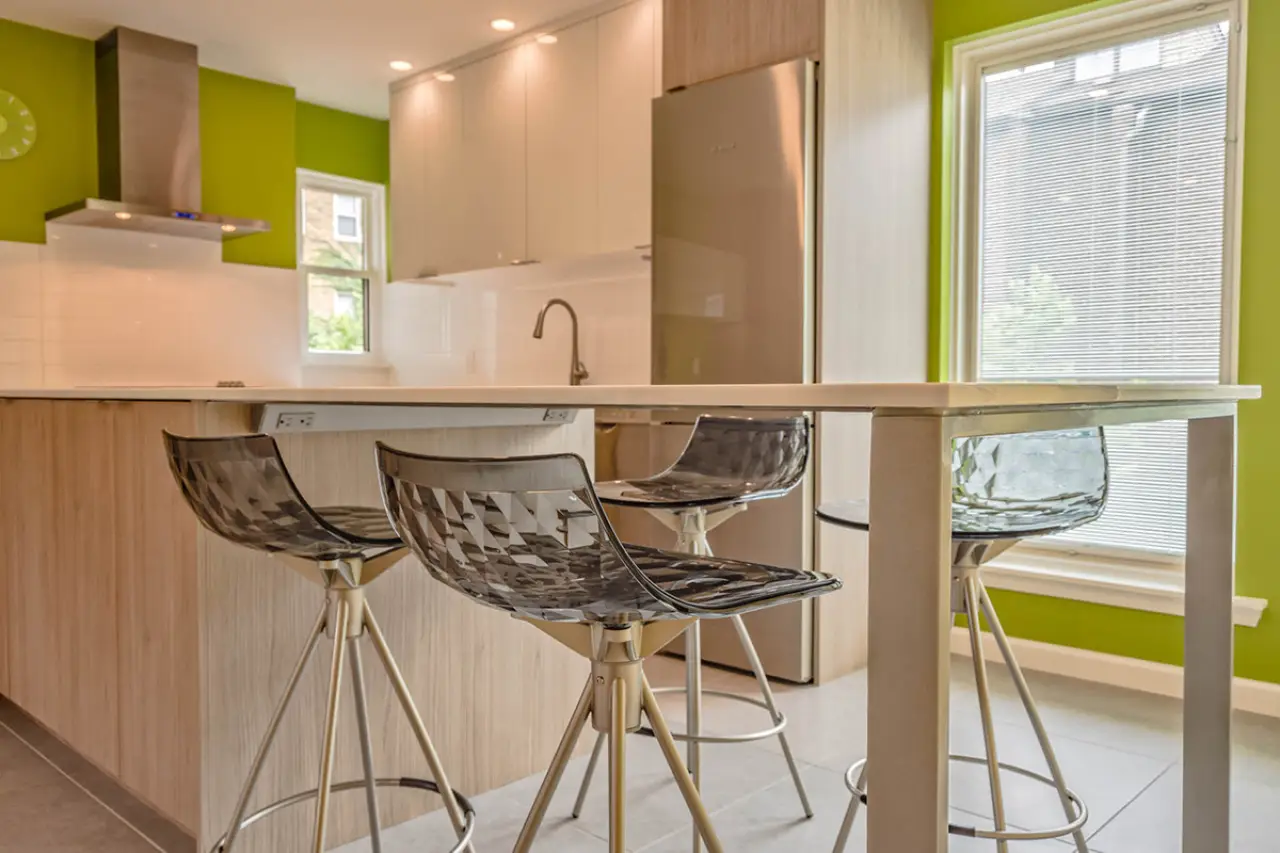 Modern kitchen with green walls, a wooden island, and three patterned barstools.