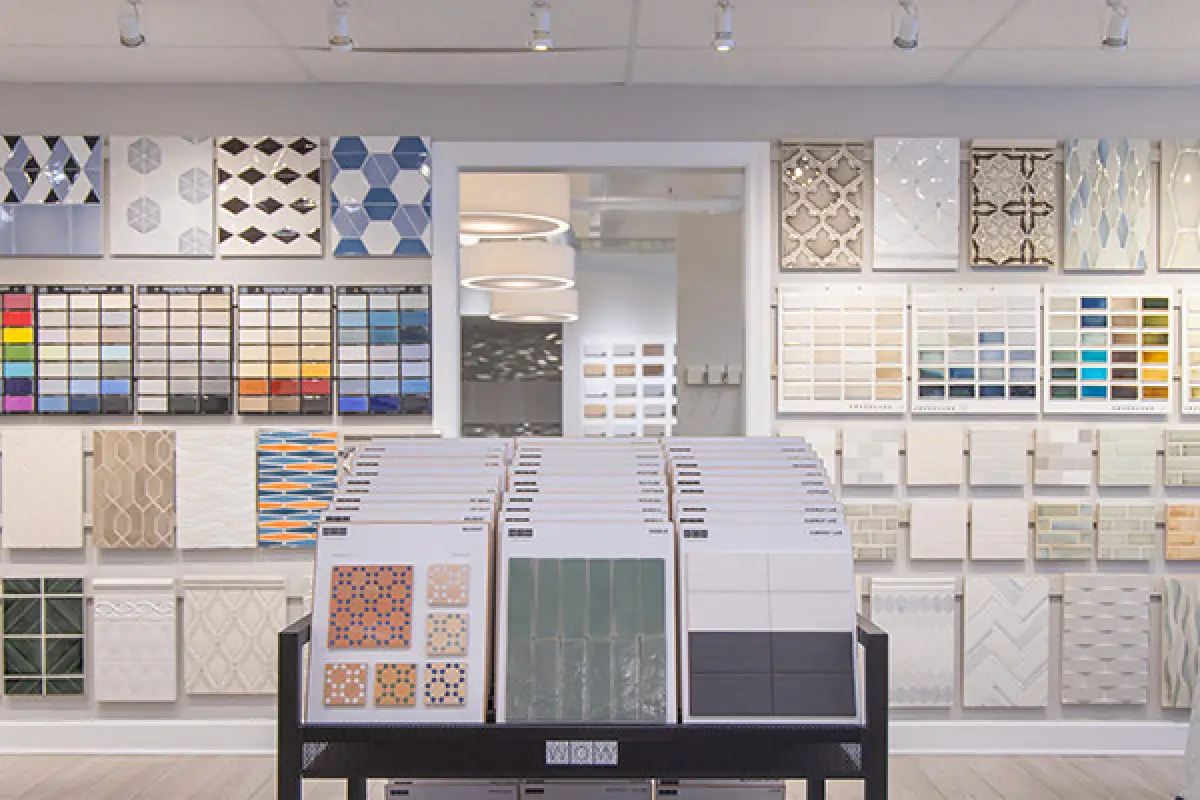 A showroom displays sample tiles and color swatches on walls and racks under bright lighting.