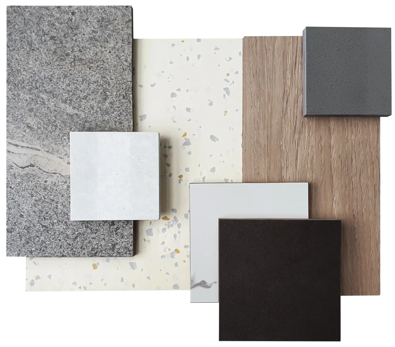 Assorted tile and stone samples in gray, white, black, and wood tones arranged on a flat surface.