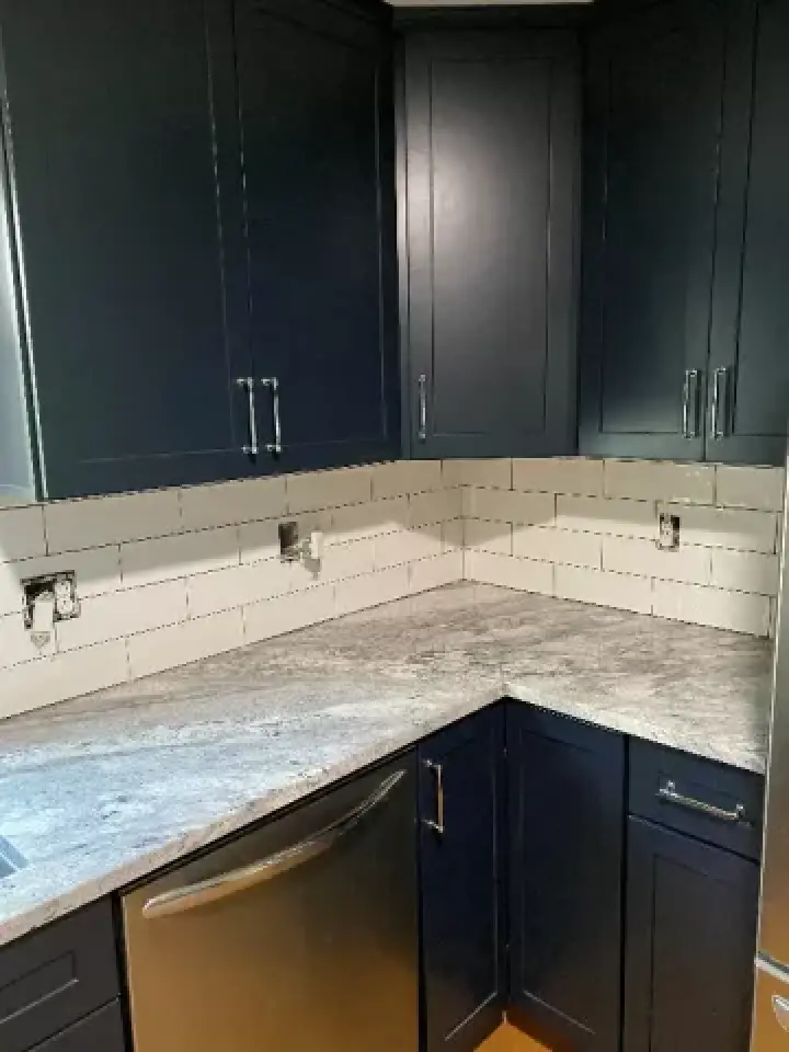 Modern kitchen corner with dark cabinets, white subway tile backsplash, and gray countertop.