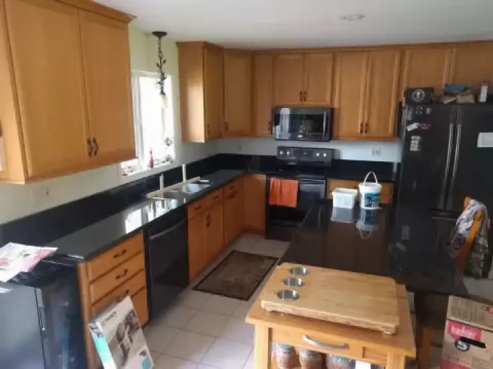 Spacious kitchen with wooden cabinets, black countertops, and stainless steel appliances.