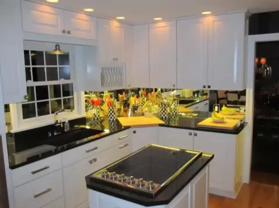 Modern kitchen with white cabinets, black countertops, and a stovetop on a central island.
