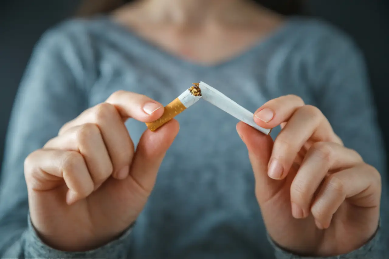 woman wearing blue shirt breaking cigarette in half