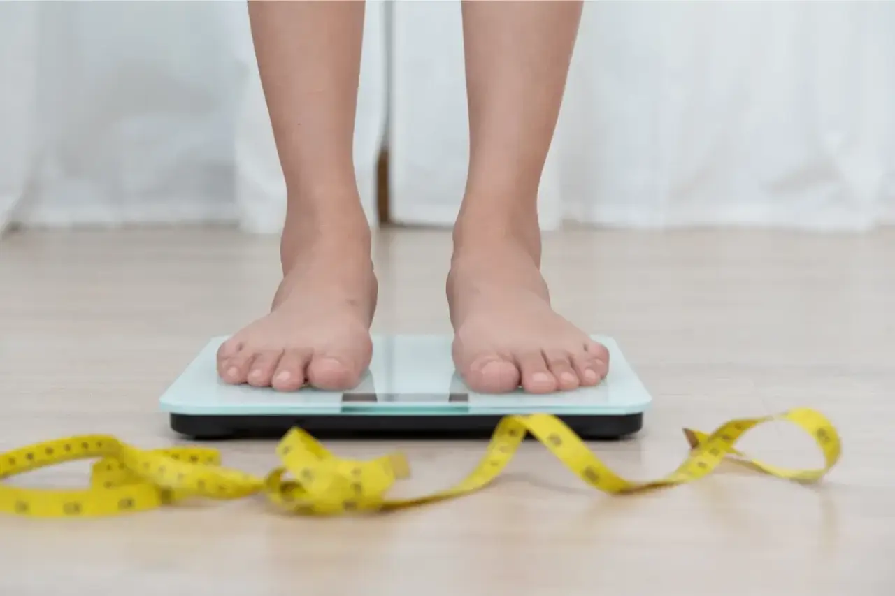 two feet standing on a scale with a yellow measuring tape