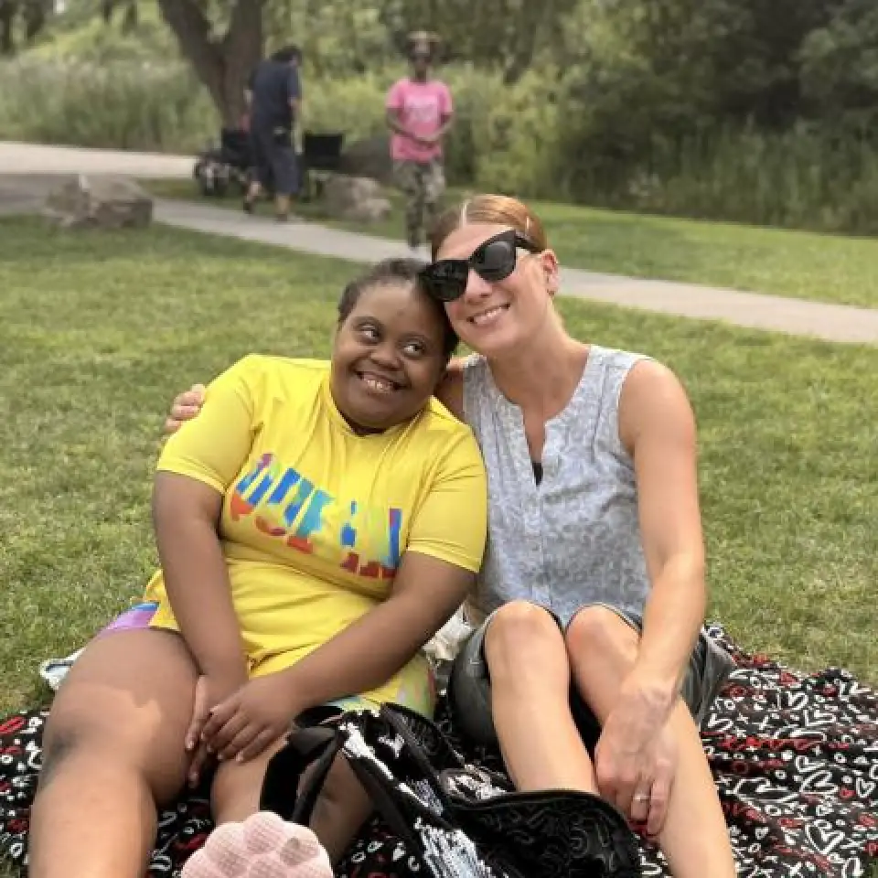 A registrant and staff member smile while sitting on a picnic blanket.