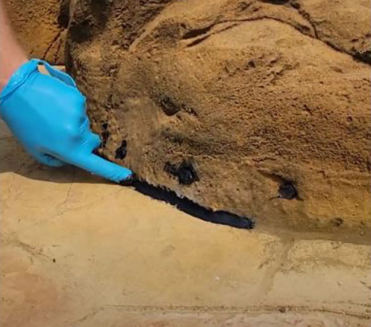 hand sealing silicone around faux rock waterfall for pool