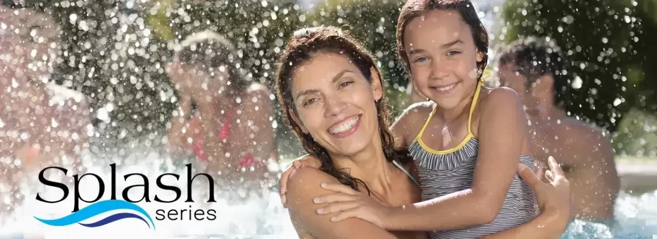 woman holding daughter in pool with splashing water