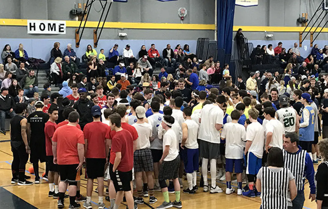 large group of students gather on a gym floor spectators sit in the bleachers
