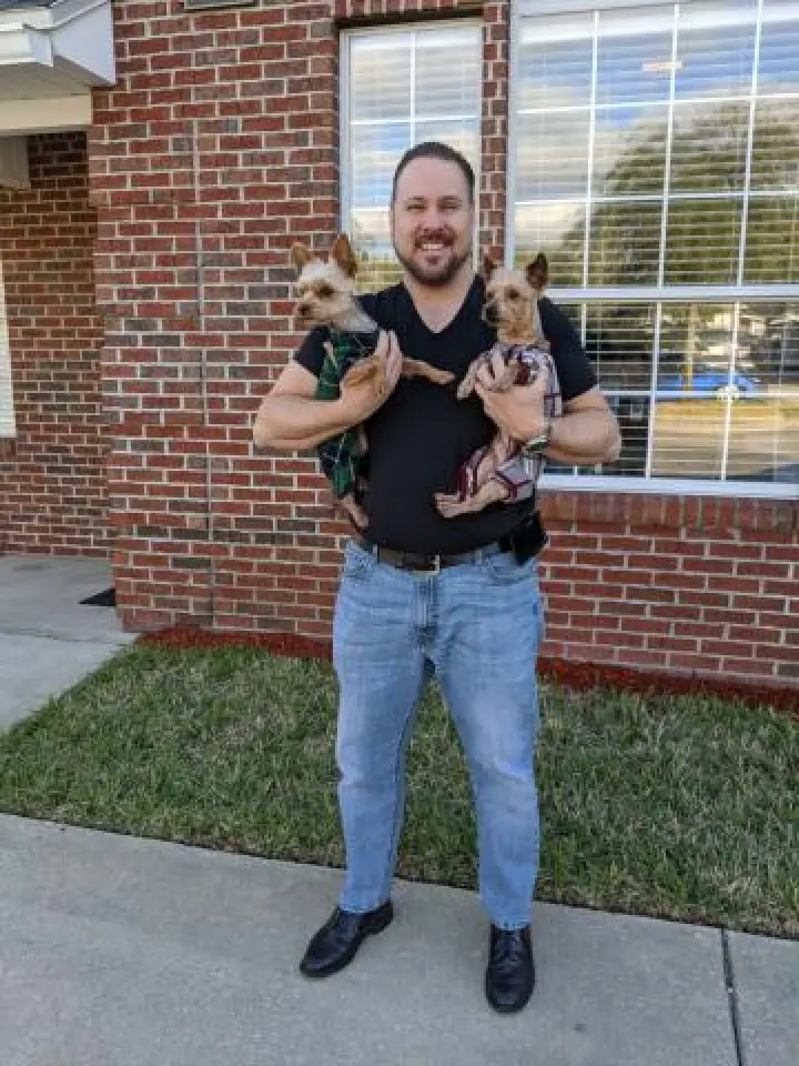 a man with two dogs in front of the office