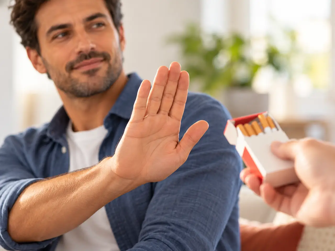 Man holding up his hand to refuse an offered pack of cigarettes