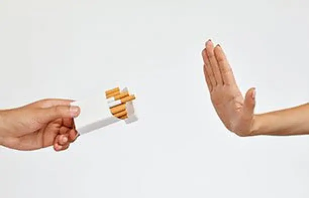 A hand offers cigarettes while another hand gestures to refuse against a plain white background.