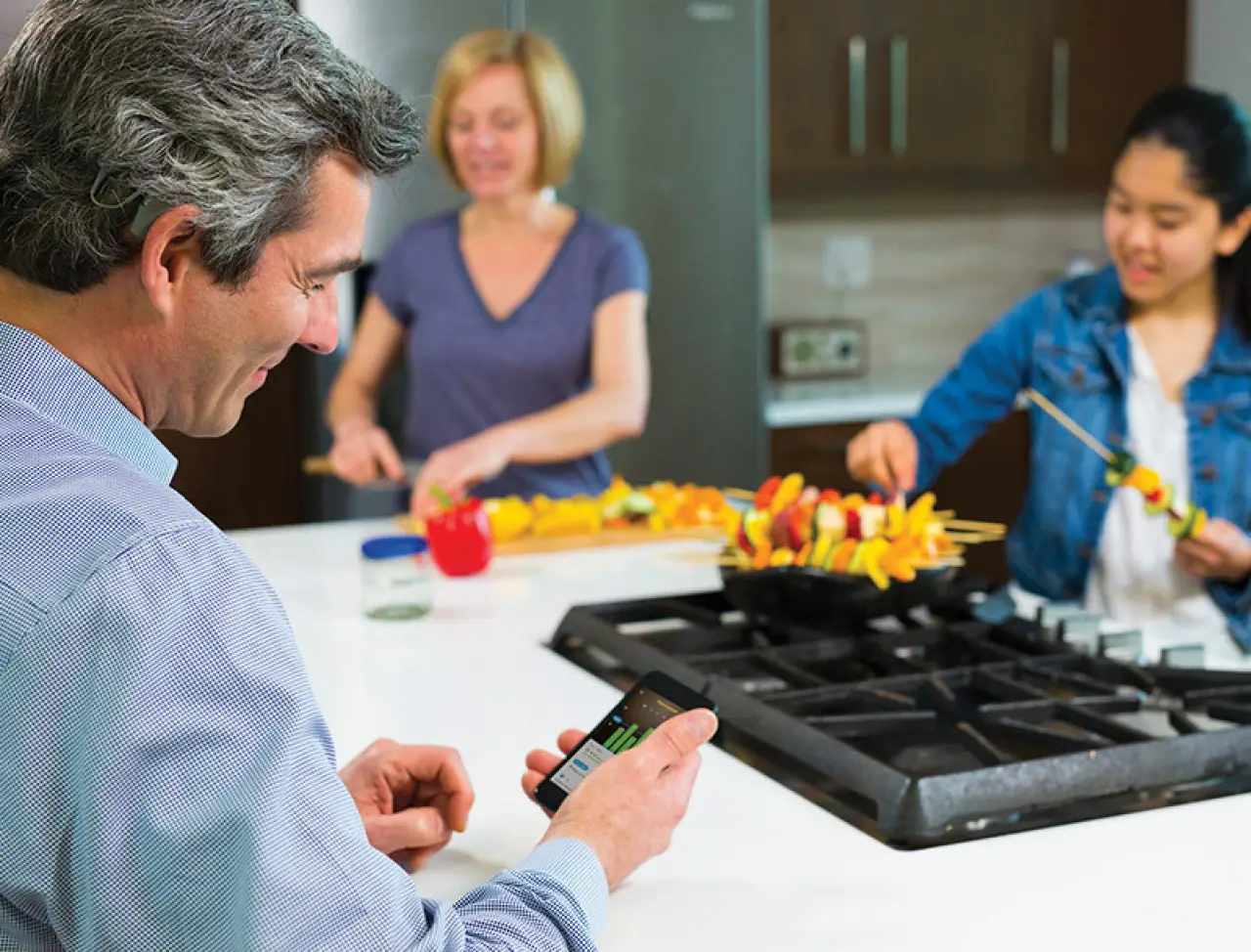 man with cochlear implant and two women cooking