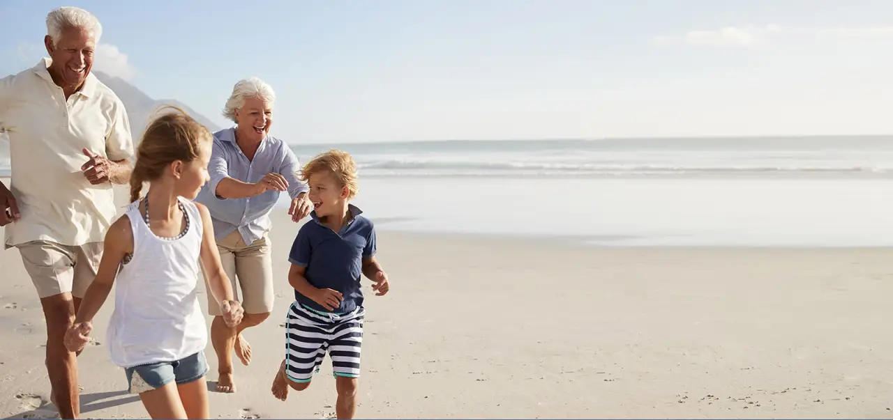 kids running on beach with grandparents