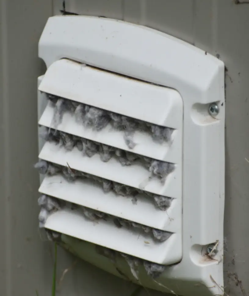 Exterior dryer vent cover clogged with lint buildup.