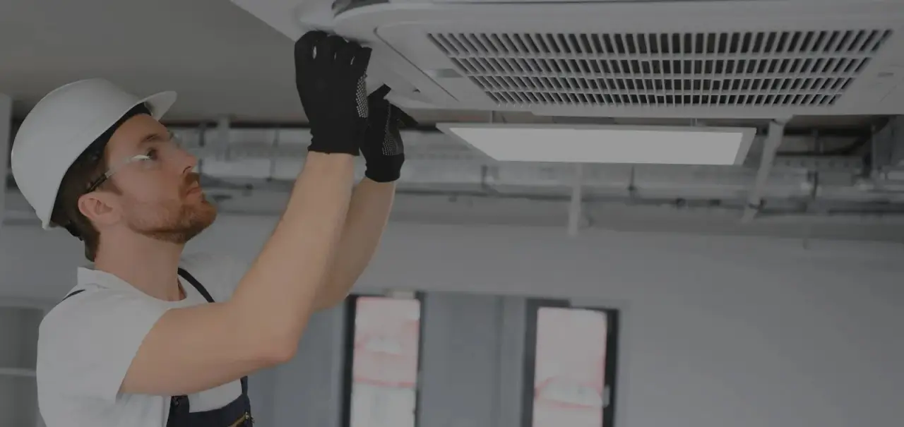 Technician inspecting a ceiling HVAC vent